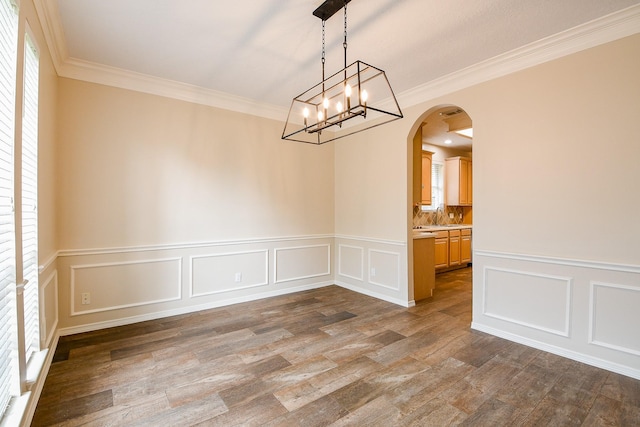 241 Blue Hill Dr, Montgomery, TX 77356 - empty room featuring a notable chandelier, a decorative wall, arched walkways, a wainscoted wall, and dark wood-style floors