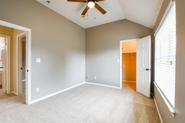 241 Blue Hill Dr, Montgomery, TX 77356 - unfurnished bedroom with a walk in closet, visible vents, baseboards, lofted ceiling, and light carpet