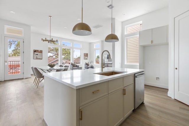 kitchen featuring stainless steel dishwasher, a sink, light countertops, and light wood-type flooring