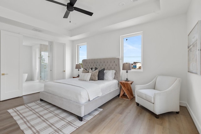 bedroom featuring visible vents, wood finished floors, baseboards, ceiling fan, and a raised ceiling