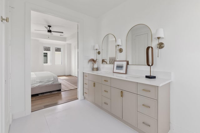 ensuite bathroom with vanity, ceiling fan, baseboards, and ensuite bath