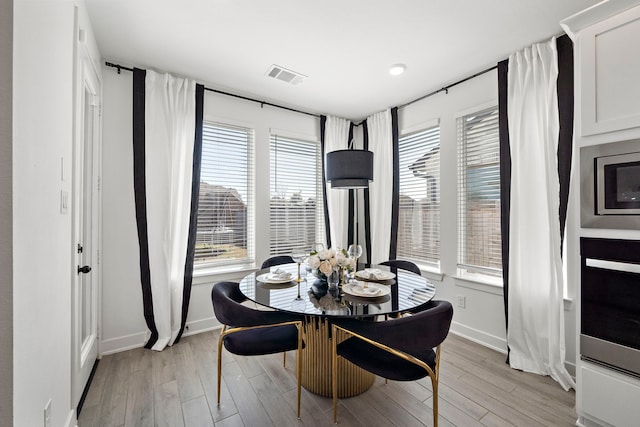 dining room with baseboards, visible vents, and light wood-style floors