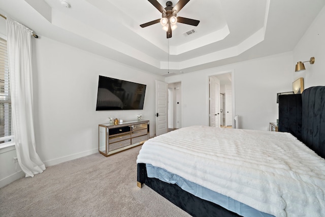carpeted bedroom featuring visible vents, baseboards, ceiling fan, and a tray ceiling
