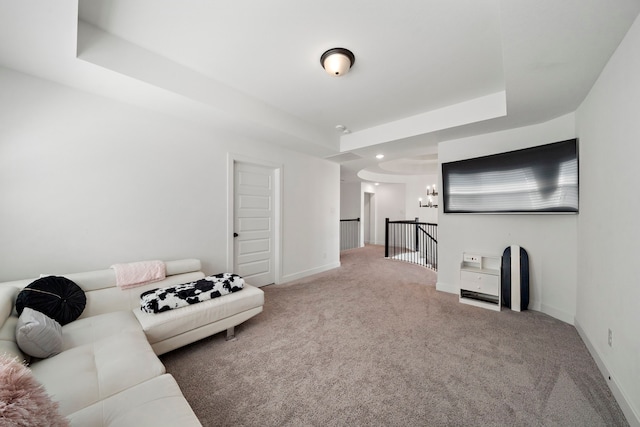 carpeted living area featuring baseboards, a notable chandelier, and a raised ceiling