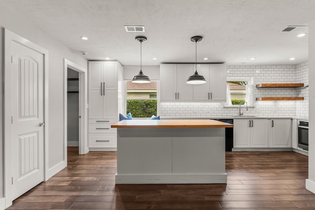 kitchen with white cabinets, a sink, stainless steel oven, dark wood finished floors, and dishwashing machine