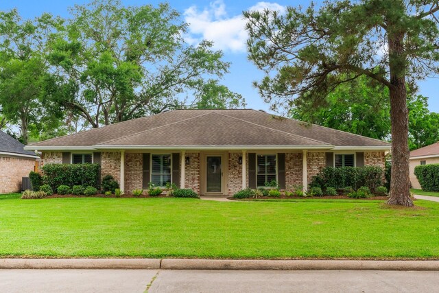 ranch-style house featuring brick siding, a shingled roof, and a front lawn
