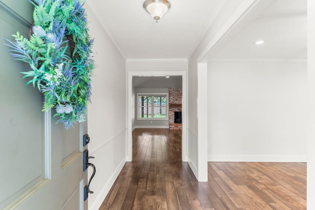 foyer featuring baseboards, ornamental molding, a fireplace, and dark wood-style flooring