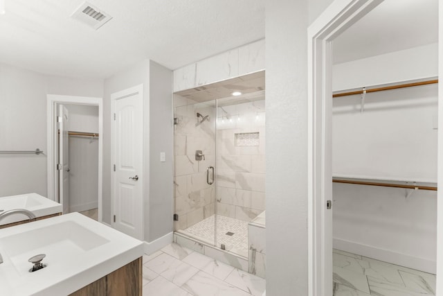 bathroom featuring visible vents, marble finish floor, baseboards, a spacious closet, and a stall shower
