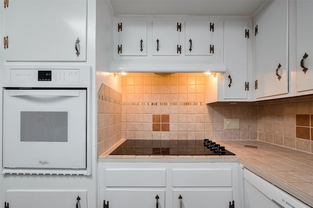kitchen with decorative backsplash, tile countertops, black electric cooktop, white cabinetry, and oven