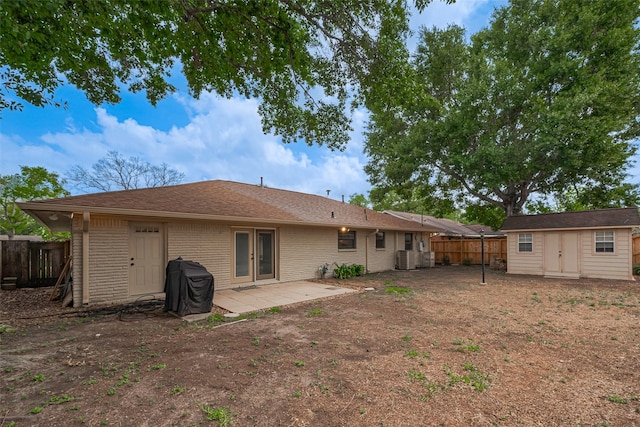 rear view of property featuring an outbuilding, a patio area, central air condition unit, fence, and a storage unit