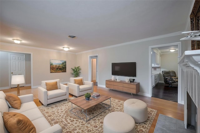 living area with crown molding, baseboards, wood finished floors, and visible vents
