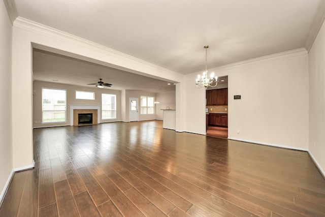 unfurnished living room with crown molding, dark wood finished floors, a glass covered fireplace, ceiling fan with notable chandelier, and baseboards