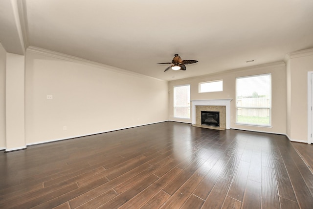 unfurnished living room featuring crown molding, baseboards, dark wood-type flooring, a high end fireplace, and a ceiling fan