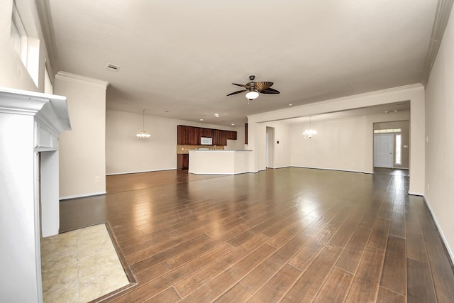 unfurnished living room with dark wood-style flooring, visible vents, ornamental molding, and ceiling fan with notable chandelier