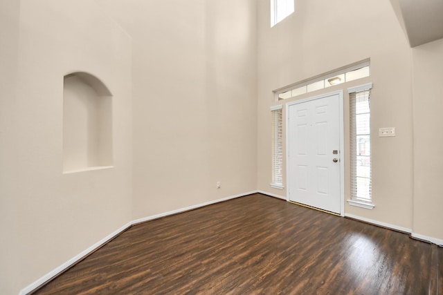 entrance foyer with baseboards, dark wood-style flooring, and a towering ceiling