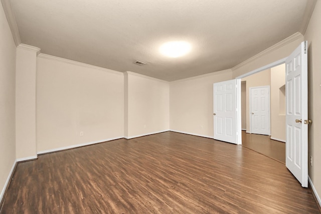 spare room with baseboards, visible vents, ornamental molding, and dark wood-type flooring