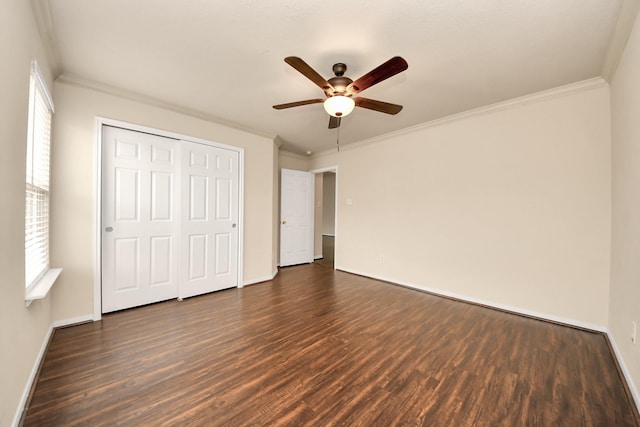 unfurnished bedroom with baseboards, ornamental molding, dark wood-style flooring, and a closet