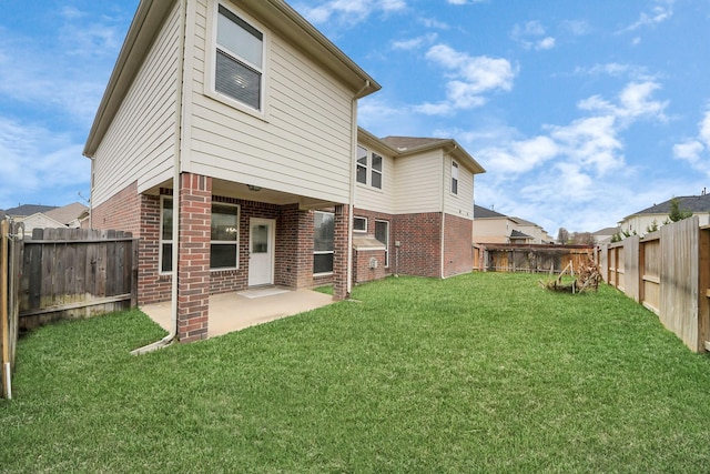 back of house with a yard, brick siding, a patio, and a fenced backyard
