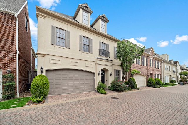 townhome / multi-family property with an attached garage, decorative driveway, and stucco siding