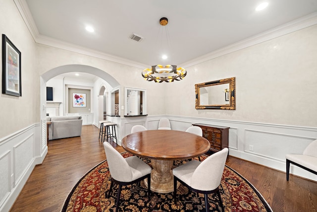 dining space with visible vents, arched walkways, crown molding, and a decorative wall