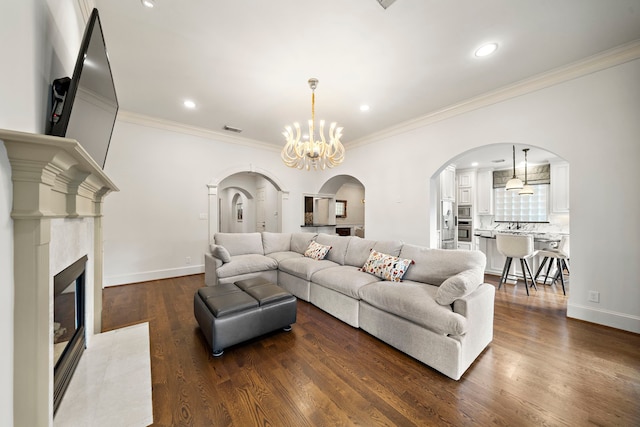 living room with crown molding, visible vents, dark wood-style floors, arched walkways, and a premium fireplace