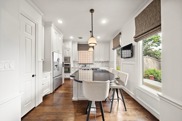 kitchen featuring built in appliances, a kitchen breakfast bar, a center island, white cabinetry, and backsplash