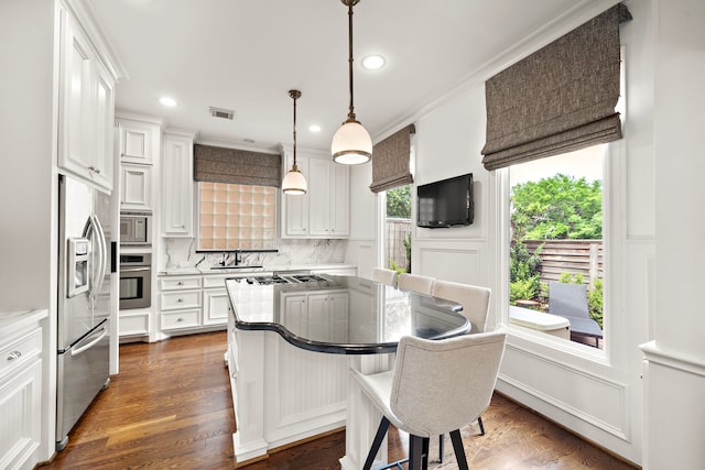 kitchen featuring a kitchen island, backsplash, stainless steel appliances, and white cabinets