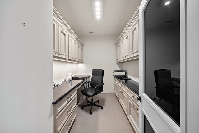 office area with light colored carpet, built in desk, and visible vents