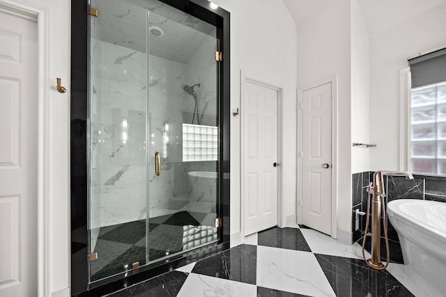 bathroom with marble finish floor, a marble finish shower, and a freestanding tub