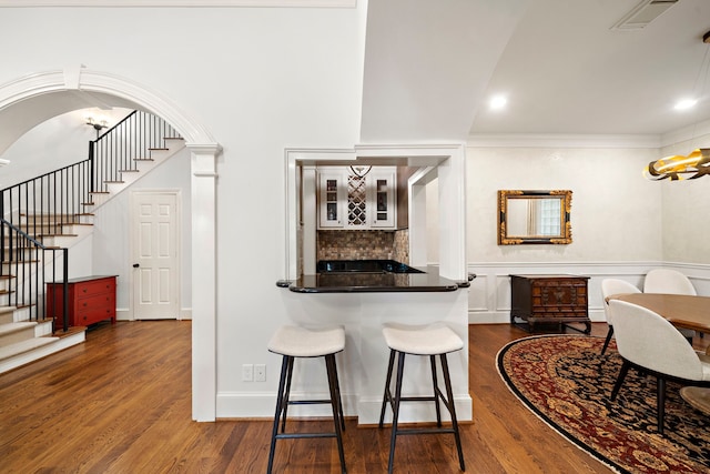 bar with decorative backsplash, indoor bar, visible vents, dark wood-style floors, and stairway