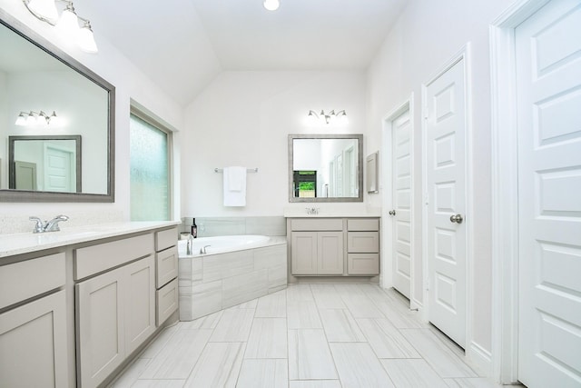 bathroom featuring vaulted ceiling, two vanities, a sink, and a bath