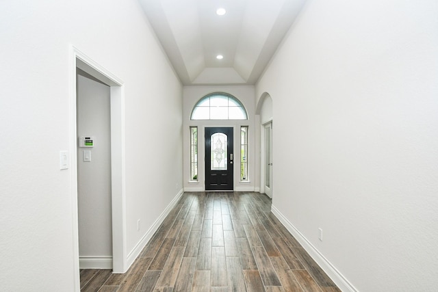 foyer featuring dark wood-type flooring, recessed lighting, baseboards, and arched walkways