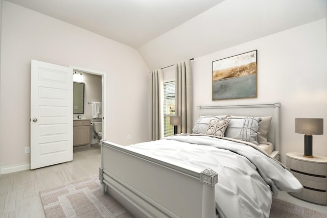 bedroom featuring baseboards, vaulted ceiling, and ensuite bath