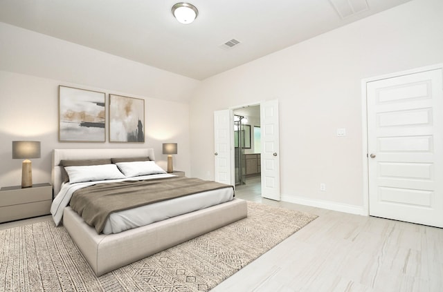 bedroom with connected bathroom, baseboards, lofted ceiling, light wood-type flooring, and visible vents