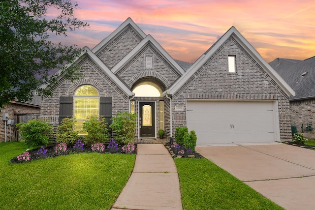 french provincial home with brick siding, a garage, driveway, and a front lawn
