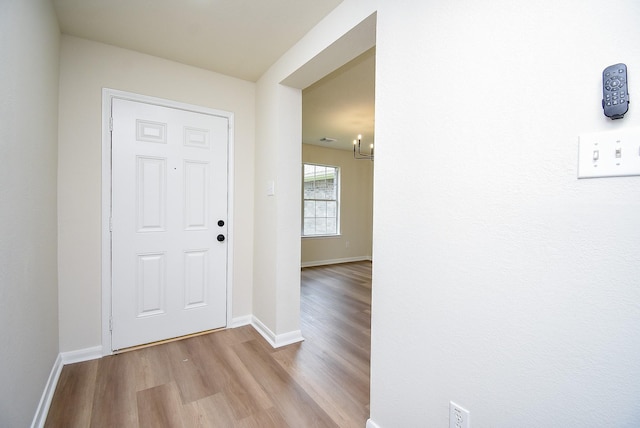 foyer entrance featuring baseboards, wood finished floors, and an inviting chandelier