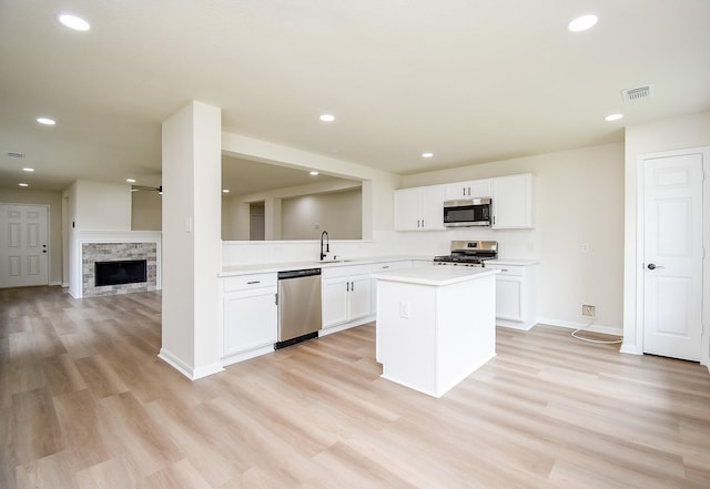 kitchen with appliances with stainless steel finishes, a sink, light countertops, a kitchen island, and visible vents