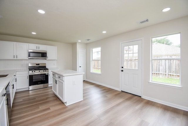 kitchen with a kitchen island, appliances with stainless steel finishes, a healthy amount of sunlight, and visible vents