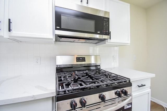 kitchen with decorative backsplash, stainless steel appliances, and white cabinetry