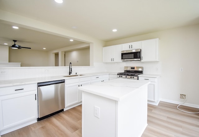kitchen featuring a sink, light wood finished floors, appliances with stainless steel finishes, and backsplash