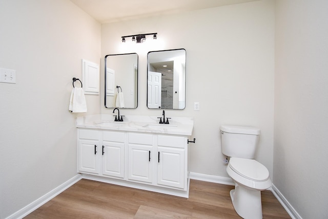full bath featuring a sink, baseboards, toilet, and wood finished floors