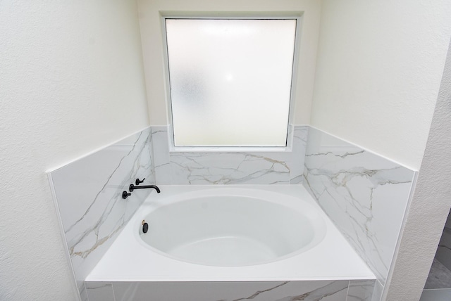 full bathroom with a garden tub and a textured wall