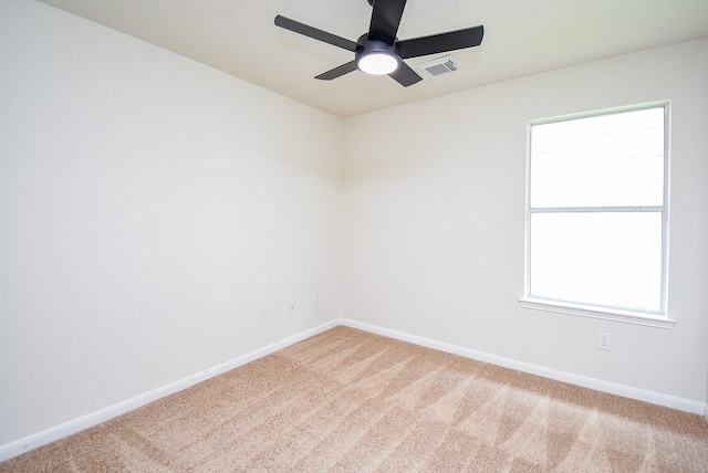 unfurnished room with carpet flooring, a ceiling fan, baseboards, a wealth of natural light, and visible vents