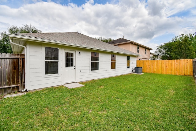 rear view of house featuring a lawn, cooling unit, and a fenced backyard