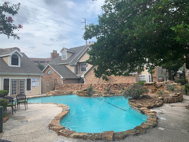 community pool featuring french doors, a patio, and an outdoor structure