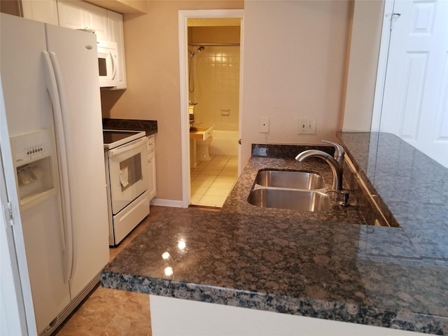kitchen featuring a sink, dark stone counters, white cabinets, and white appliances