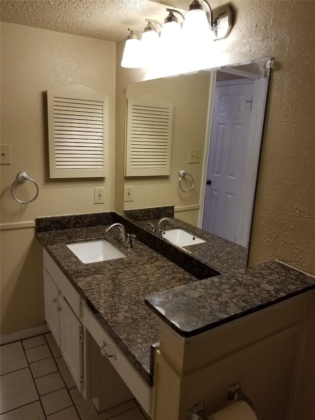 bathroom featuring a textured ceiling, tile patterned floors, a textured wall, and vanity