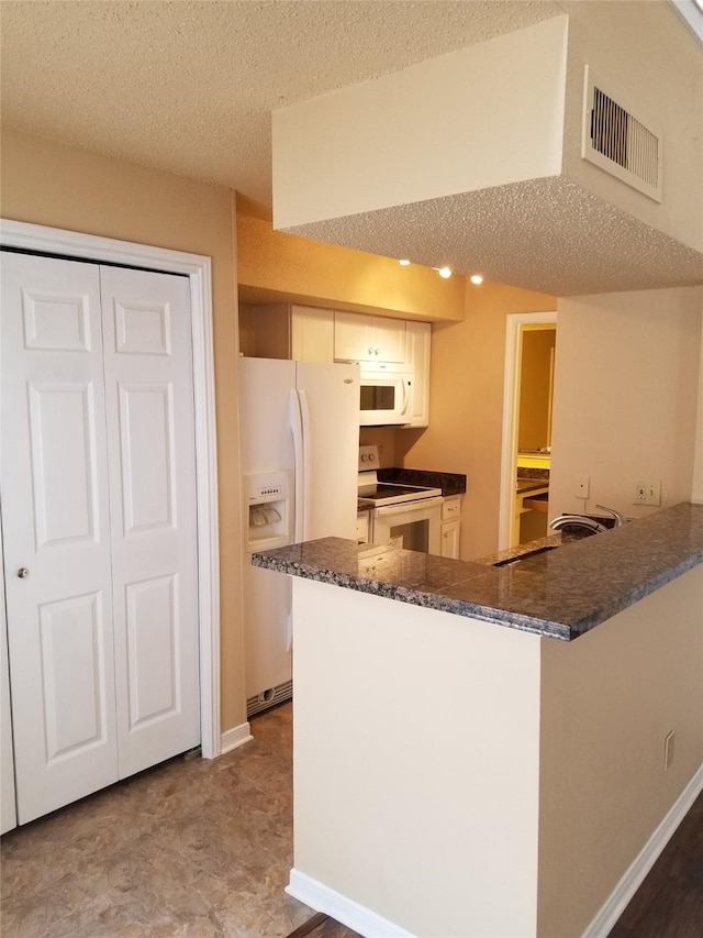 kitchen featuring a textured ceiling, visible vents, a sink, a peninsula, and white appliances