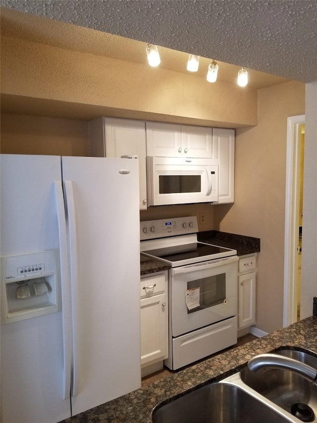 kitchen with white cabinetry, dark stone countertops, and white appliances