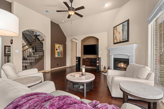 living room with a warm lit fireplace, a ceiling fan, hardwood / wood-style flooring, and lofted ceiling